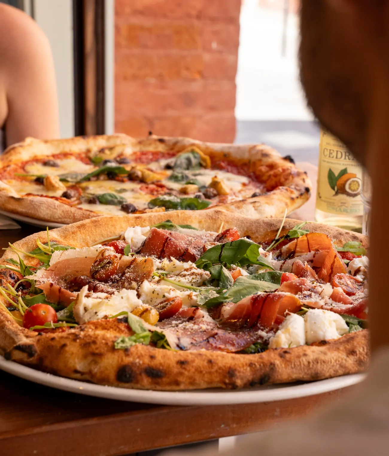 Deux pizzas napolitaines sur une table du Zinc, devant le mur de briques
