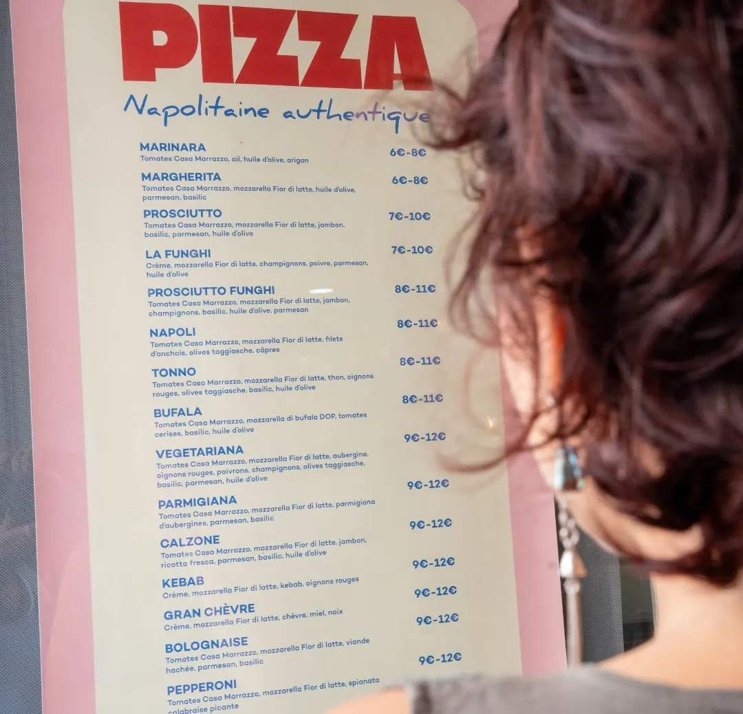 Une cliente lit la grande carte « Pizza, napolitaine authentique »