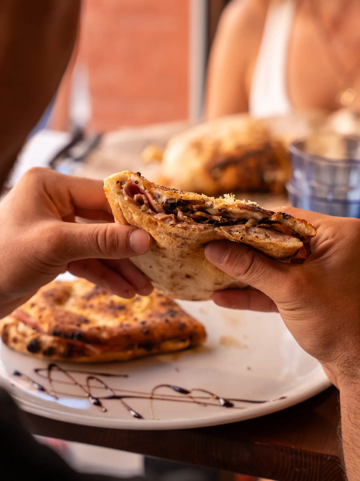 Un panuozzo garni tenu à deux mains, au-dessus de l’assiette