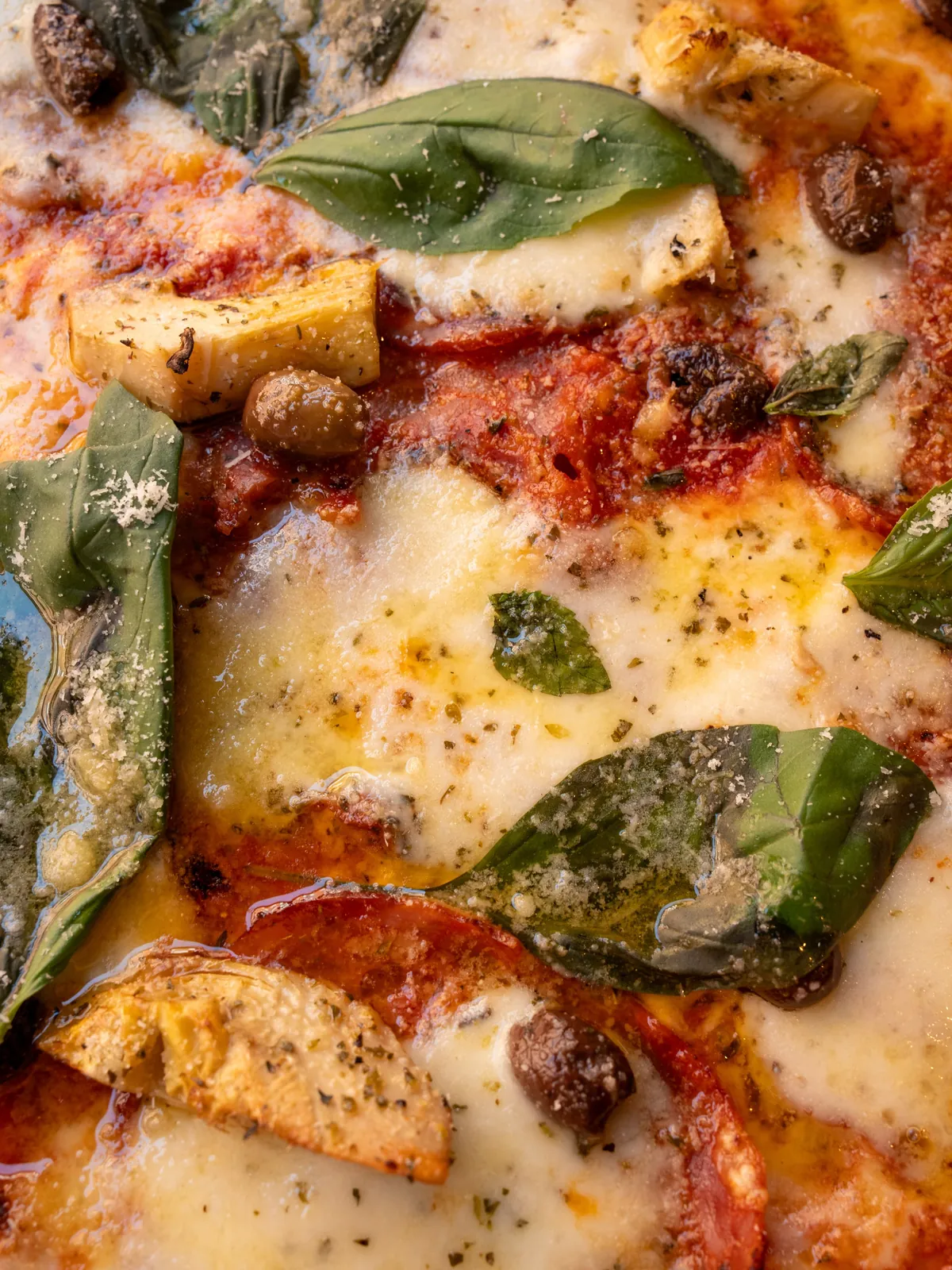 Une Diavola en gros plan : artichauts, olives et basilic