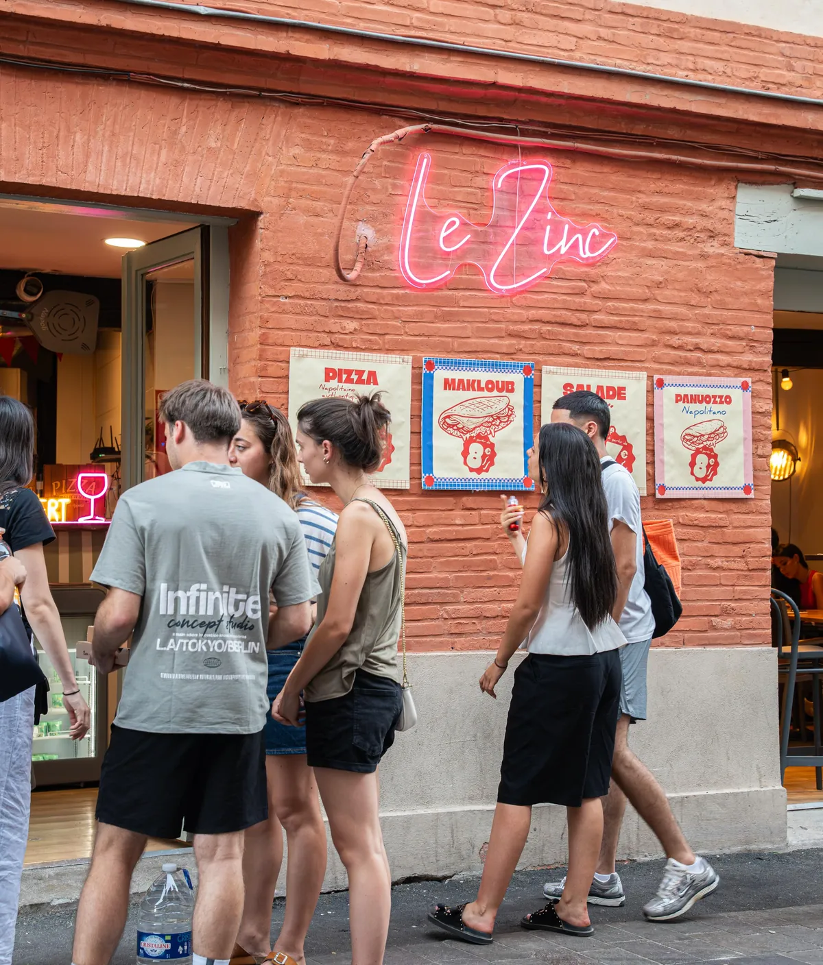 La façade du Zinc rue Valade : briques, néon rose et les quatre affiches